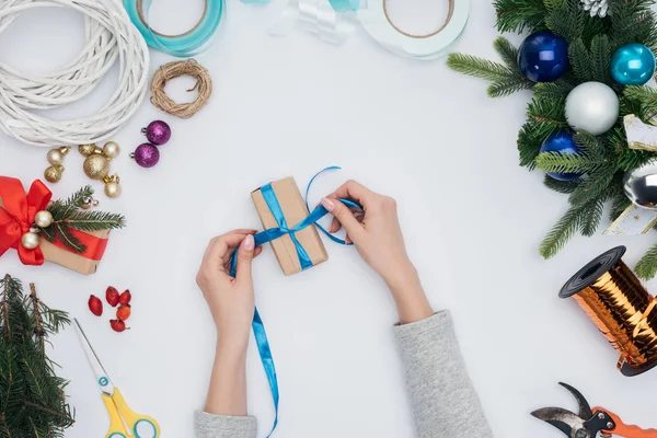 Tiro recortado de mujer envolviendo regalo de Navidad con cinta azul aislado en blanco - foto de stock