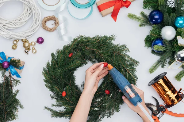 Tiro recortado de mujer decorando corona de Navidad hecha a mano con bayas de brezo aisladas en blanco - foto de stock