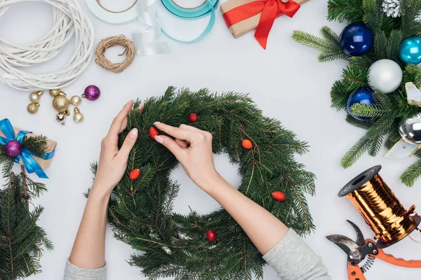 Tiro recortado de mujer decorando corona de Navidad hecha a mano con bayas de brezo aisladas en blanco - foto de stock