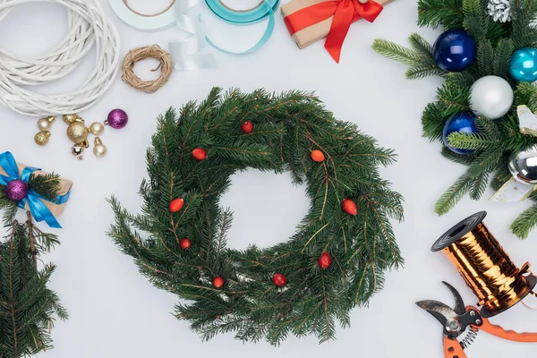 Vista superior de decorações de grinalda de natal artesanal, tesouras e fitas isoladas em branco — Fotografia de Stock