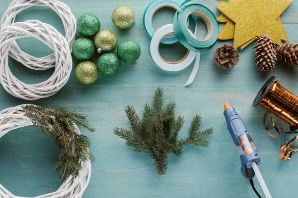 Pose plate avec boules de Noël, branches de pin et pistolet à colle pour couronne de Noël à la main — Photo de stock