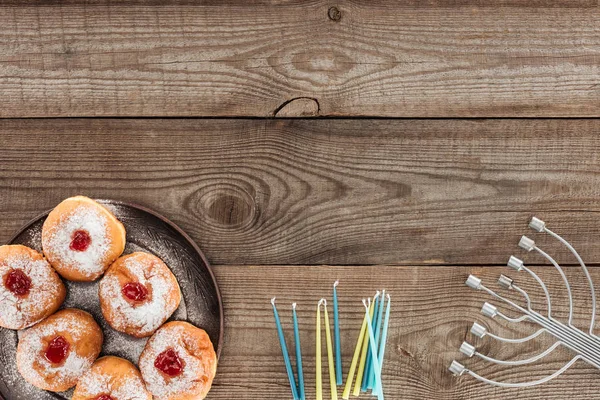 Vista superior de donuts doces e menorah com velas na mesa de madeira, conceito de celebração hannukah — Fotografia de Stock