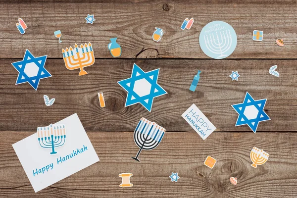 Couché plat avec la carte heureuse de hannukah et les signes de papier de vacances sur le dessus de table en bois, concept de hannukah — Photo de stock