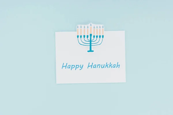 Vista superior de la tarjeta feliz hannukah y el signo de menorah de papel aislado en azul, concepto hannukah - foto de stock
