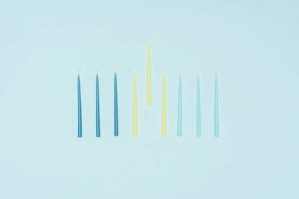 Flat lay with blue and yellow candles for hannukah holiday isolated on blue, hannukah concept — Stock Photo