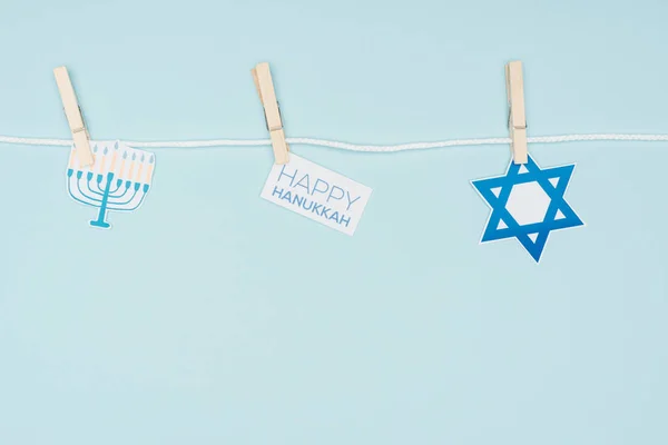 Vista superior de carteles de papel de vacaciones hannukah fijados en la cuerda aislada en azul, concepto hannukah - foto de stock