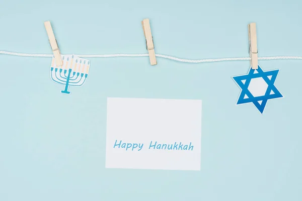 Vue du haut de la carte heureuse hannukah et des panneaux de papier de vacances fixés sur la corde isolée sur le bleu, concept hannukah — Photo de stock