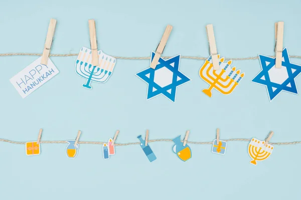 Vue du dessus des panneaux de papier de vacances hannukah accrochés à une corde isolée sur bleu, concept hannukah — Photo de stock