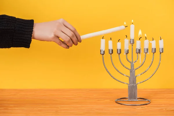 Partial view of woman lighting candles on menorah isolated on yellow, hannukah holiday concept — Stock Photo