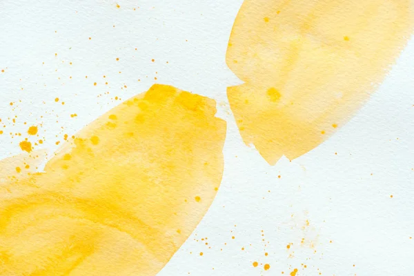 Yellow watercolor strokes with splatters on white paper background — Stock Photo