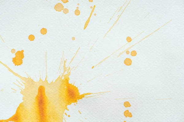 Künstlerische orangefarbene Spritzer und Kleckse auf weißem Papier — Stockfoto