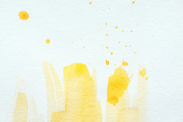 Gelbe Aquarellstriche und Spritzer auf weißem Papierhintergrund — Stockfoto
