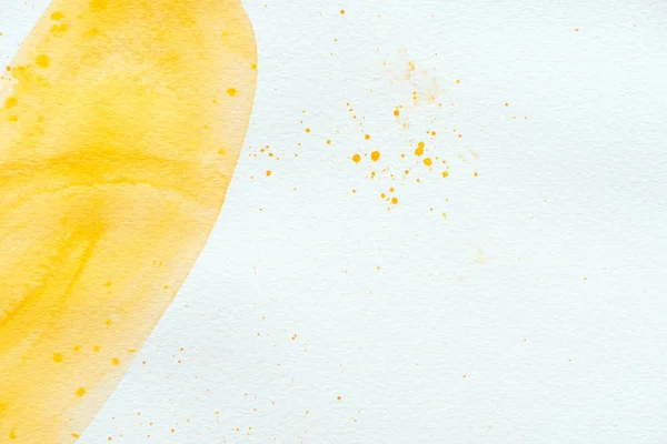 Abstract yellow watercolor stroke and splatters on white paper background — Stock Photo