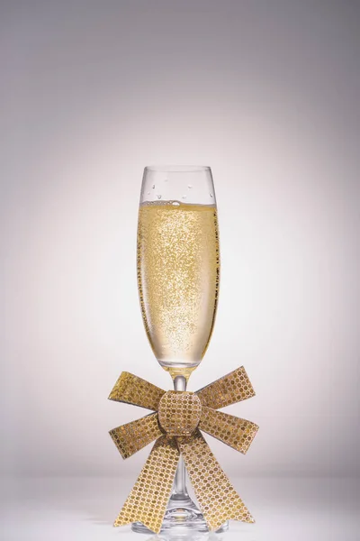 Close up view of glass of champagne with ribbon on grey backdrop — Stock Photo