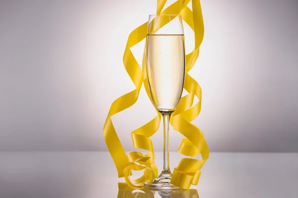 Vista de cerca de la copa de champán y confeti amarillo sobre fondo gris — Stock Photo