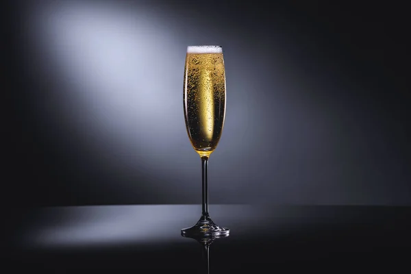 Close up view of glass of champagne with foam on dark backdrop — Stock Photo