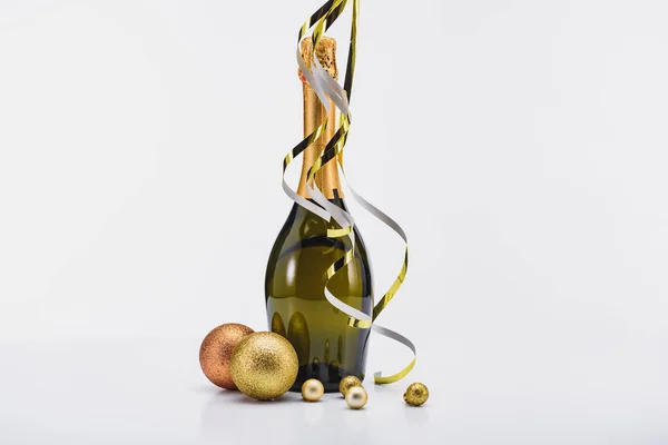 Close up view of bottle of champagne with confetti and christmas toys on white backdrop — Stock Photo