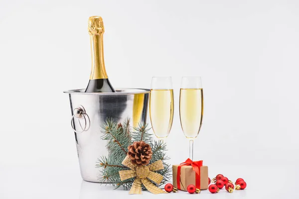 Nahaufnahme einer Flasche Champagner im Eimer, Sektgläser und verpacktes Weihnachtsgeschenk auf grauem Hintergrund — Stockfoto
