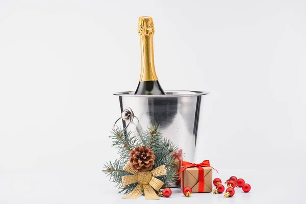 Close up view of bottle of champagne in bucket, christmas toys and wrapped gift on grey backdrop — Stock Photo