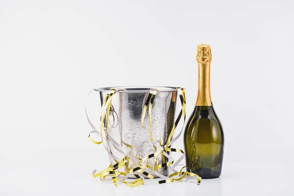 Vista de cerca de la botella de champán y cubo con guirnaldas festivas sobre fondo gris - foto de stock