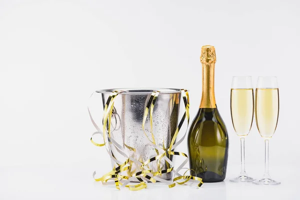 Закрыть вид ведра с конфетти, бутылкой и бокалами шампанского на сером фоне — стоковое фото