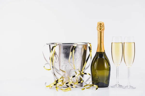 Vista de cerca del cubo con confeti, botella y copas de champán sobre fondo gris - foto de stock