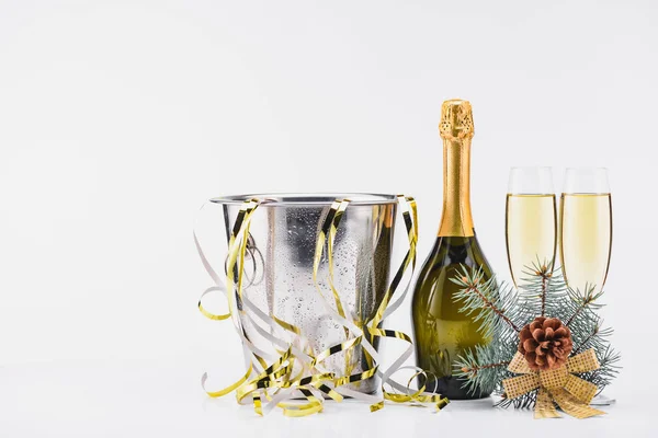 Vista de cerca del cubo con confeti, botella y copas de champán sobre fondo gris - foto de stock