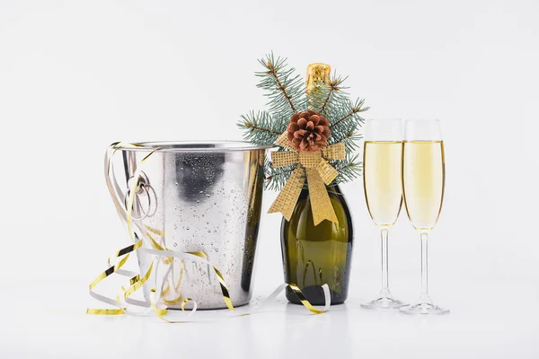 Vista de cerca del cubo con confeti, botella y copas de champán sobre fondo gris - foto de stock