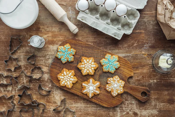 Vista superior do arranjo com biscoitos de Natal na tábua de corte, ingredientes e cortadores de biscoitos na mesa de madeira — Fotografia de Stock