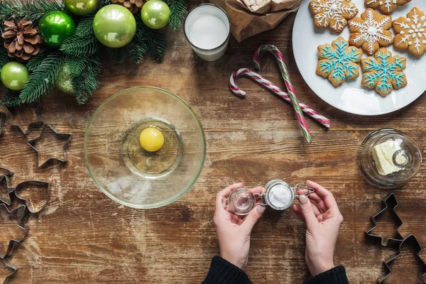 Cropped shot of woman making dough for christmas cookies on wooden tabletop with decorative wreath — Stock Photo