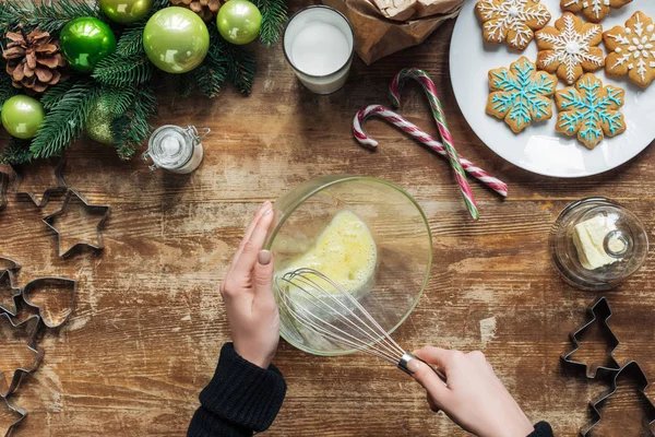 Tiro recortado de la mujer haciendo masa para galletas de Navidad en la mesa de madera con corona decorativa - foto de stock