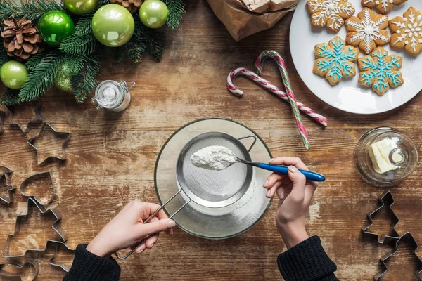 Abgeschnittene Aufnahme einer Frau, die Teig für Weihnachtsplätzchen backt, auf Holztischplatte mit dekorativem Kranz — Stockfoto