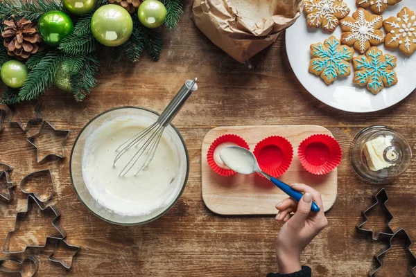 Vista parcial de la mujer vertiendo masa en formas de hornear en la mesa de madera, concepto de hornear de Navidad - foto de stock