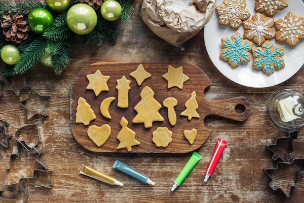 Vista superior do arranjo da massa crua, tinta de grau alimentício para padaria de biscoitos de Natal e grinalda de Natal em mesa de madeira — Fotografia de Stock