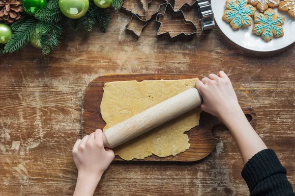 Abgeschnittene Aufnahme einer Frau, die Teig mit Nudelholz für Weihnachtsplätzchen auf einer hölzernen Tischplatte rollt — Stockfoto