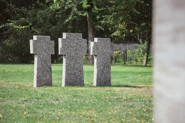 Old identical tombstones placed in row on grass at cemetery — Stock Photo