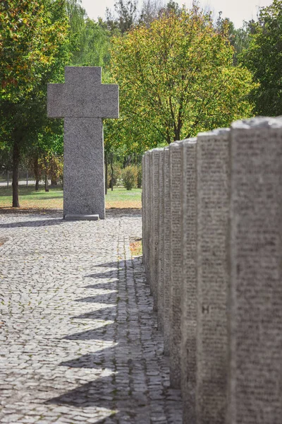 Cruz de piedra y tumbas idénticas con letras colocadas en fila en el cementerio - foto de stock