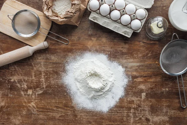 Vista superior de farinha branca e ingredientes de cozimento na mesa de madeira — Fotografia de Stock