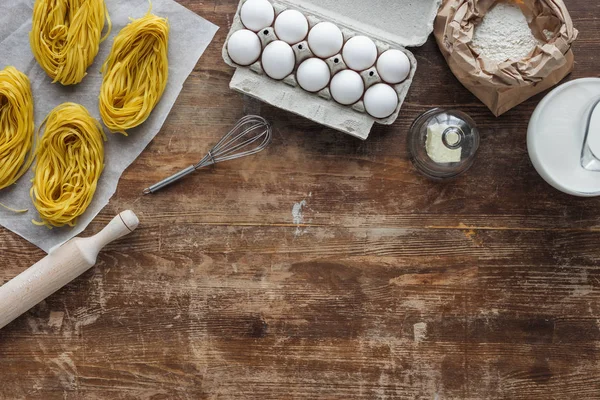 Top view of uncooked pasta and raw ingredients on wooden table — Stock Photo