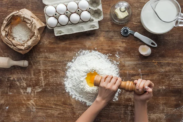 Vista superior de las manos femeninas añadiendo sal a la harina en la mesa de madera — Stock Photo