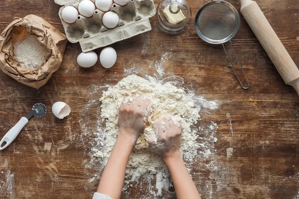 Vista dall'alto di mani femminili che fanno la pasta su tavolo di legno — Foto stock