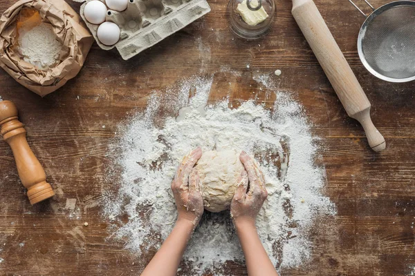 Top view of female hands forming dough on wooden table — Stock Photo