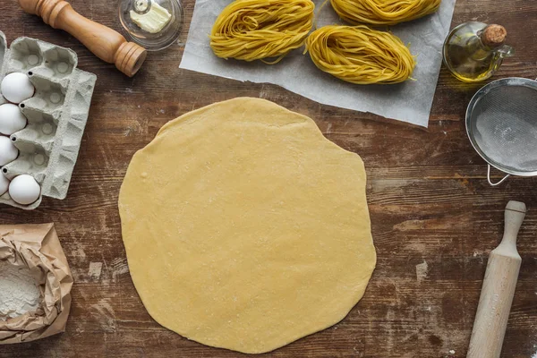 Top view of rolled dough for pasta on wooden table — Stock Photo