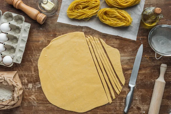 Top view of cut raw dough for pasta on wooden table — Stock Photo