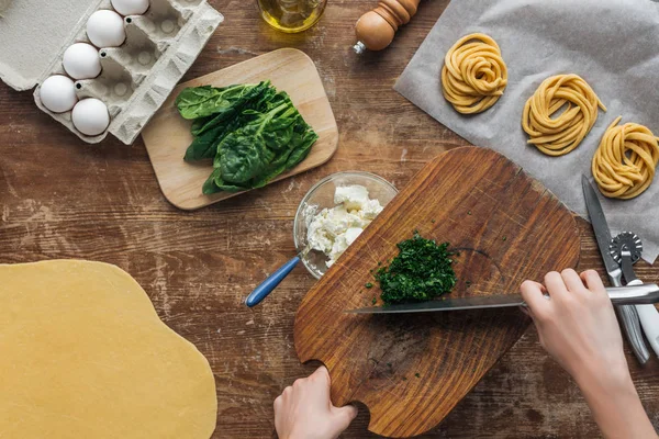 Top view of female hands chopping spinach on wooden table — Stock Photo