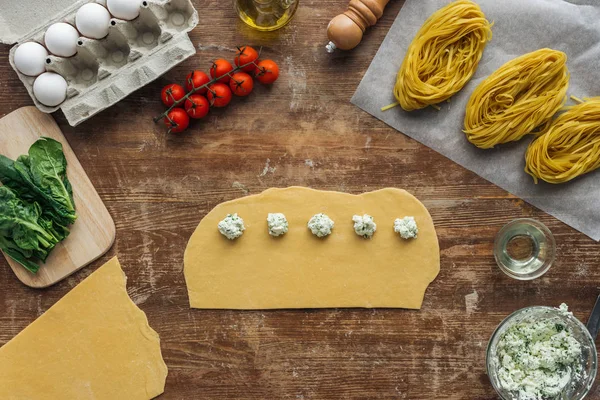 Vista superior do recheio de queijo cremoso na massa crua para ravioli na mesa de madeira — Fotografia de Stock