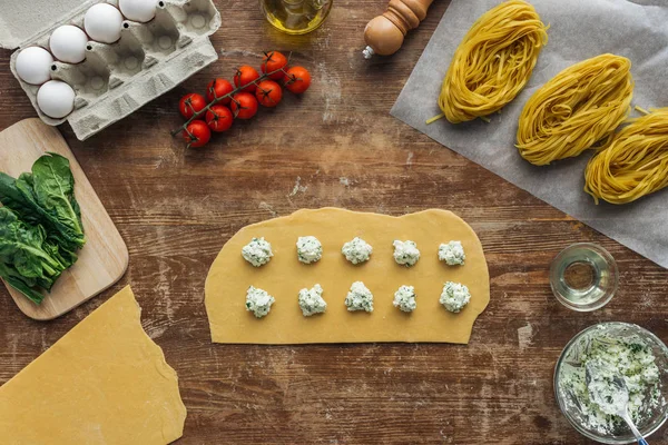 Vista dall'alto di ripieno di formaggio cremoso su pasta cruda per ravioli a tavola di legno — Foto stock