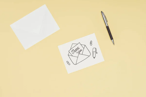Cartão branco com letras de agradecimento saindo do envelope desenhado à mão e caneta isolada no fundo amarelo — Fotografia de Stock