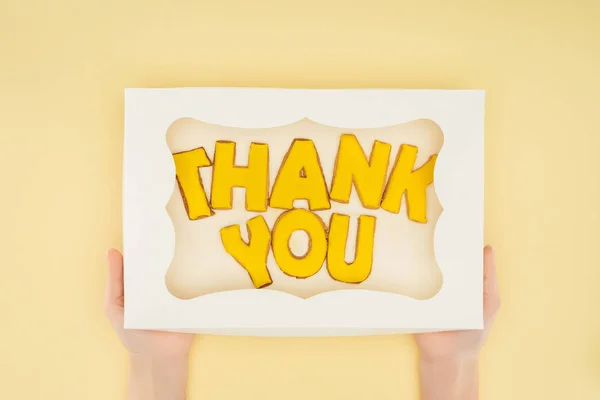 Persona ritagliata con torta quadrata in scatola con scritte di ringraziamento isolate su sfondo giallo — Foto stock