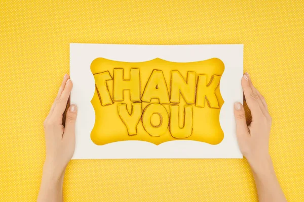 Persona recortada sosteniendo pastel en forma cuadrada en caja con letras de agradecimiento aislado sobre fondo amarillo - foto de stock